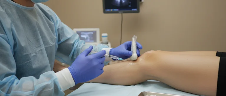 Врач вводит инъекцию в коленный сустав